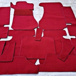 Puede incluir: Un juego de alfombrillas de coche rojas. Las alfombrillas están hechas de un material suave y mullido y están diseñadas para adaptarse a los contornos del suelo del coche.