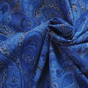May include: A fabric featuring a dense, intricate paisley pattern in various shades of blue, including royal, navy, and light blue. The design consists of repeating teardrop-shaped motifs, swirling floral elements, and fine black line details.