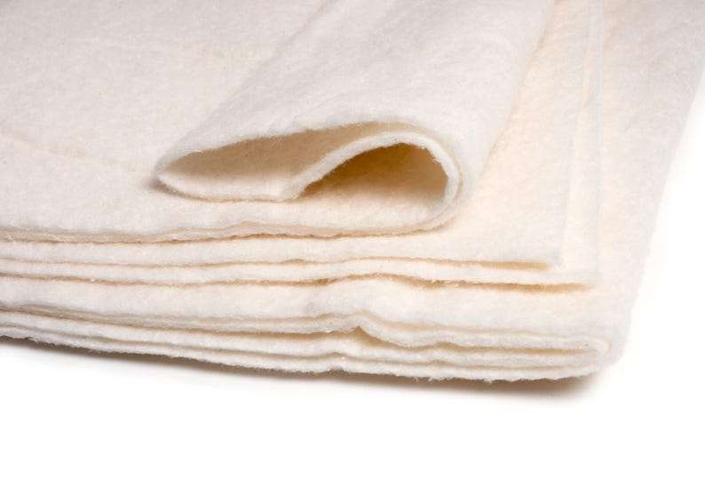 May include: A stack of white cotton batting, folded in half, with the edges of the layers visible.