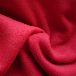 May include: A close-up of a soft, red fleece fabric. The fabric is folded and draped, showing its texture and colour.