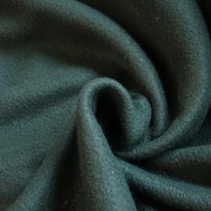 May include: A close-up of a soft, dark green fleece fabric. The fabric is folded and textured, showing the plushness of the material.