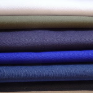 May include: A stack of fabric swatches in various colours, including white, green, navy blue, royal blue, and dark blue.