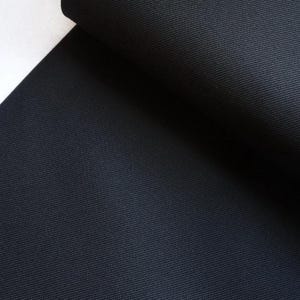 May include: Close-up of a dark blue fabric with a subtle ribbed texture. The fabric is folded over, showing the smooth surface on the inside.