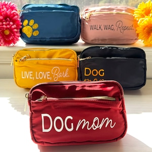 May include: Five different small zippered bags with various dog-themed embroidery. The bags are in the colors red, yellow, blue, black, and pink. The text on the bags reads "WALK, WAG, Repeat.", "LIVE, LOVE, Bark.", "DOG", and "DOG mom".