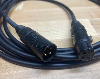 May include: A black XLR cable with gold-plated connectors. The cable is coiled and the connectors are visible.