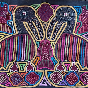 Könnte beinhalten: Ein Textilkunstwerk mit einem symmetrischen Design aus stilisierten Vögeln und geometrischen Formen. Die Vögel haben gestreifte Flügel in leuchtenden Farben, darunter Rot, Lila und Blau, vor einem schwarzen Hintergrund. Das Kunstwerk ist mit goldenen und weißen Nähten umrandet.