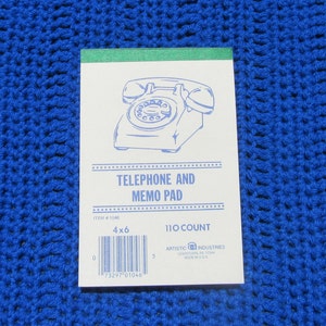 May include: White telephone and memo pad with a blue rotary phone graphic. The pad is 4x6 inches and has the text "TELEPHONE AND MEMO PAD". The pad has a green top edge and is on a blue crocheted surface.