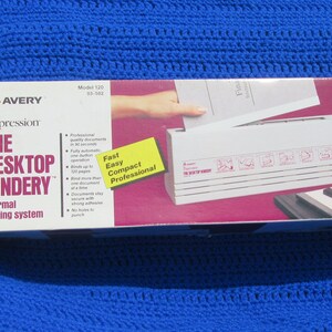 May include: A white Avery Impression Desktop Bindery thermal binding system in a white box with a pink and white background. The box has text that reads "Avery Impression The Desktop Bindery Thermal Binding System" and "Fast Easy Compact Professional". The box also has a yellow sticker that reads "Use with Impression Covers".