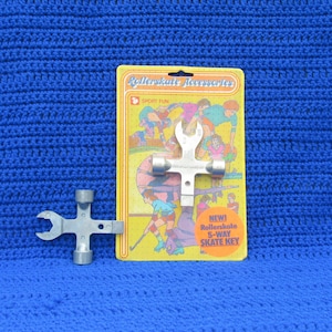 May include: A yellow and orange package with a silver 5-way roller skate key. The package has the text "Rollerskate Accessories" and "Sport Fun" on it. The key is a multi-tool with different sized wrenches and sockets.
