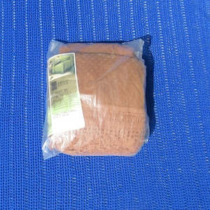 May include: A brown furniture throw cover in a plastic bag. The bag has a label that reads "Embroidered Beauty Furniture Throw Cover Large Sofa & Throw Sizes 144 x 91"