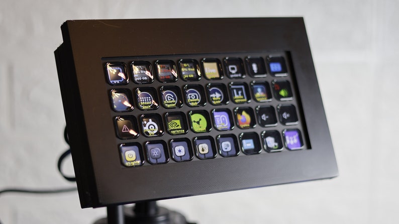 May include: A black control panel with a grid of 36 square buttons, each with a different icon. The buttons are illuminated with a variety of colors, including yellow, green, blue, and red.