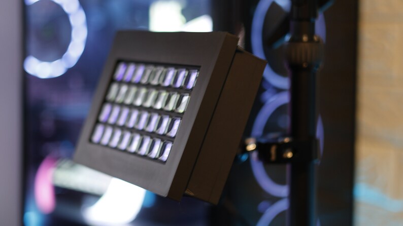 May include: A black light panel with a grid of white LED lights. The panel is mounted on a black stand.