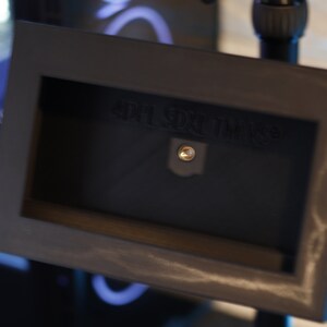 May include: A black metal frame with a small rectangular opening. The frame has a screw in the center and the text "HDR SUN TIME" is visible.