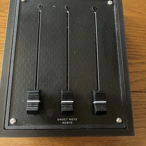 Könnte beinhalten: Schwarzer Audiomixer mit drei Knöpfen und dem Text "Ghost Note Audio" auf der Vorderseite.