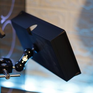 May include: A black tablet screen mounted on a black adjustable arm with a silver knob. The arm is attached to a black tripod stand with a silver knob.