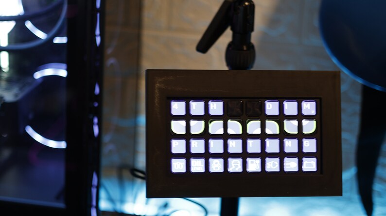 May include: A black framed keyboard with white keys and a light blue backlight. The keys are labeled with letters and symbols, including "PRINTING".