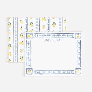 May include: A white stationery card and matching envelope featuring a blue hand-painted border with yellow lemons and small floral motifs. The card displays the text A Note From Julia in blue script, while the envelope has a repeating lemon pattern.