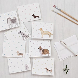 8 assorted white horizontal greeting cards, each with a different watercolor dog in the lower right corner and tiny hearts in a variety of colors.