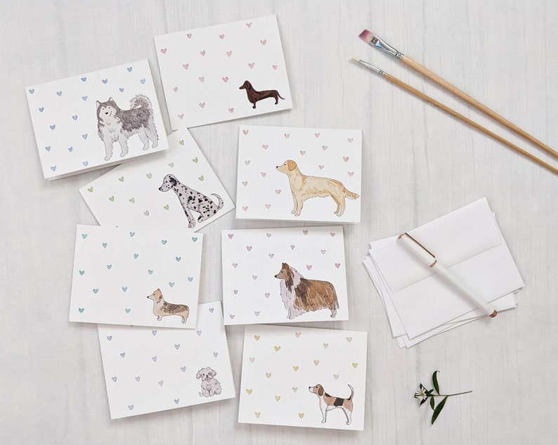8 assorted white horizontal greeting cards, each with a different watercolor dog in the lower right corner and tiny hearts in a variety of colors.