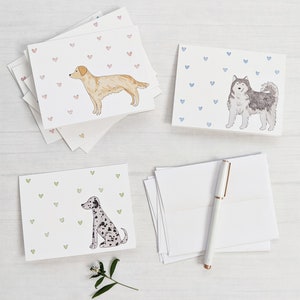 Peut inclure: Quatre cartes de v&oelig;ux vierges illustrant diff&eacute;rentes races de chiens. Les cartes ont un fond de petits c&oelig;urs roses, bleus ou verts. Les chiens sont un golden retriever, un husky, un dalmatien et un terrier.