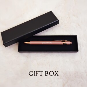 K&ouml;nnte beinhalten: Ein ros&eacute;goldener Stift mit dem eingravierten Namen "Jacqueline", pr&auml;sentiert in einer schwarzen Geschenkbox. Der Stift hat einen goldfarbenen Clip und eine Spitze. Die Worte "GIFT BOX" sind unten im Bild aufgedruckt.