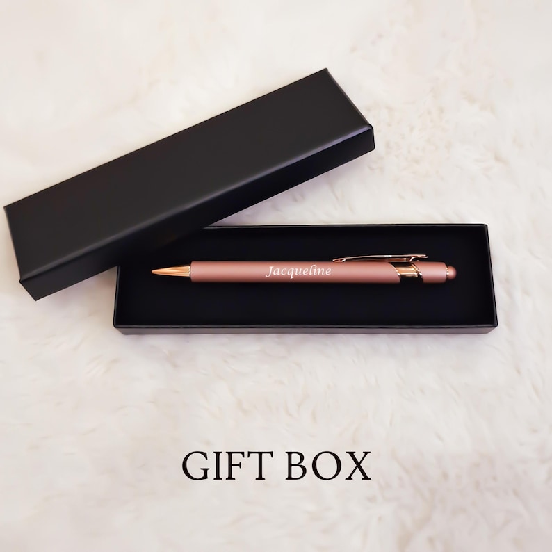 K&ouml;nnte beinhalten: Ein ros&eacute;goldener Stift mit dem eingravierten Namen "Jacqueline", pr&auml;sentiert in einer schwarzen Geschenkbox. Der Stift hat einen goldfarbenen Clip und eine Spitze. Die Worte "GIFT BOX" sind unten im Bild aufgedruckt.