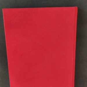 Op de afbeelding: Een stevig rood hardback boek zonder zichtbare tekst of afbeeldingen op de omslag.