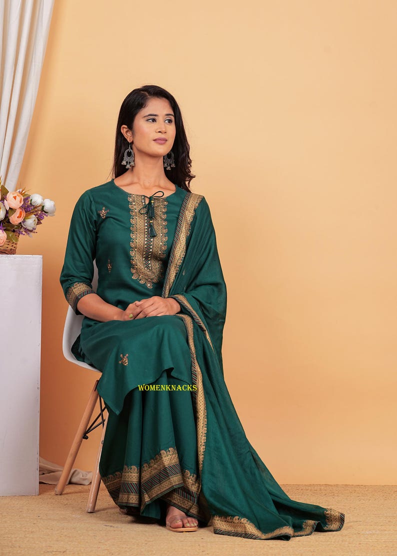 May include: A green kurta with gold embroidery and a matching dupatta. The kurta has a tie-up neckline and three-quarter sleeves. The dupatta has a gold border.