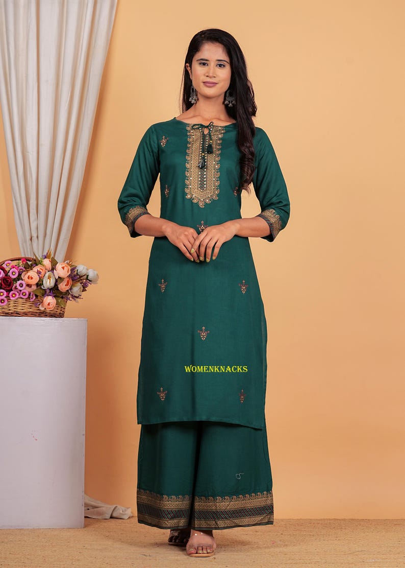 May include: A green kurta and palazzo set with gold embroidery. The kurta has a round neckline and three-quarter sleeves. The palazzo pants have a wide leg and a gold border.