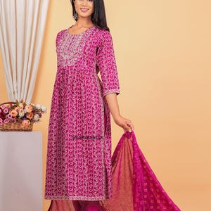 May include: A magenta and white patterned kurta with a matching dupatta and pants. The kurta has a round neckline and three-quarter sleeves. The dupatta is sheer and has a floral pattern. The pants are slim-fitting and have a straight leg.