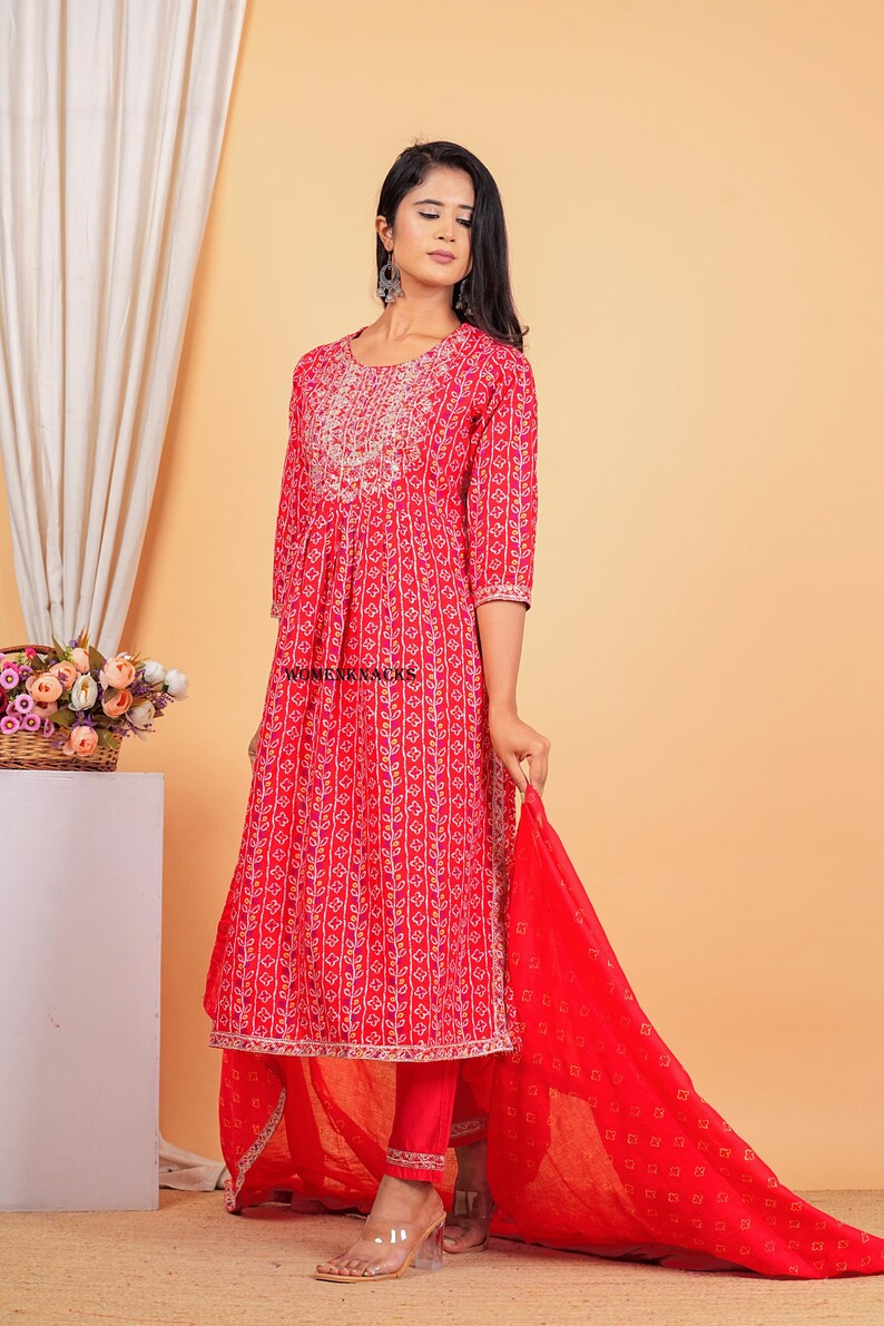 May include: A red printed kurta with a matching red palazzo pant and a red dupatta. The kurta has a floral print and a white embroidered neckline. The dupatta has a small geometric print.