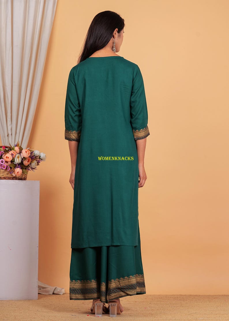May include: A teal green long kurta with gold trim on the sleeves and bottom hem. The kurta is paired with a matching teal green skirt with gold trim. The skirt has a layered design.