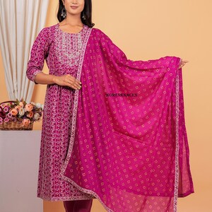 May include: A magenta kurta with a white floral print and a matching magenta palazzo pant. The kurta has a white embroidered neckline and the set includes a magenta dupatta with a white border and a small square print.