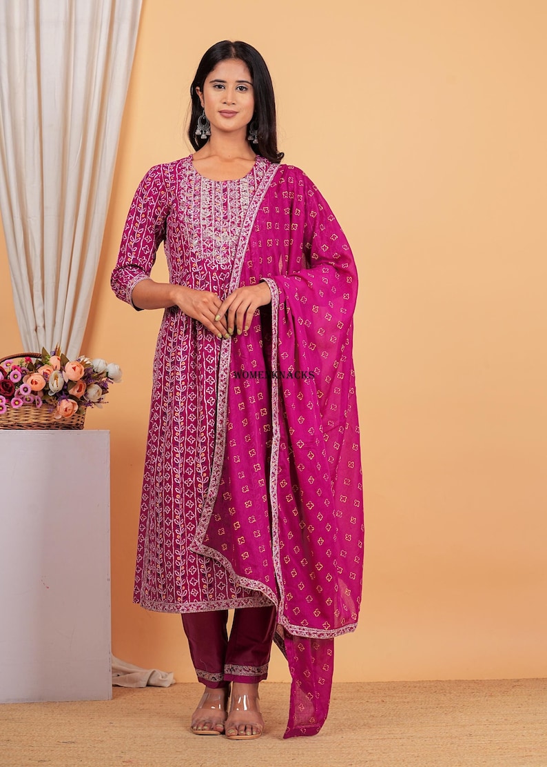 May include: A magenta and white printed kurta with a matching pair of pants and a magenta dupatta. The kurta has a round neckline and three-quarter sleeves. The dupatta has a printed border.