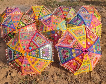 May include: A collection of colorful, open decorative umbrellas with intricate embroidered patterns. The umbrellas feature a variety of colors, including pink, yellow, blue, and green, with mirrored accents and fringed edges. The designs include floral and elephant motifs.