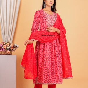 May include: A red and white printed kurta with a matching red palazzo pant and a red dupatta. The kurta has a round neckline and three-quarter sleeves. The dupatta has a floral print and a gold border. The outfit is perfect for a special occasion.