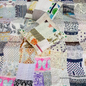 Op de afbeelding: Een patchwork quilt en twee bijpassende vierkante kussens met diverse bedrukte stofresten in wit, roze, blauw, groen en zwart. De textielstukken zijn verbonden met zichtbaar wit rijgwerk en bevatten de tekst Womenknacks.