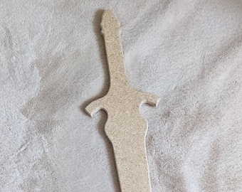May include: A wooden sword cutout, with a light brown color and a simple design. The sword is lying flat on a white fuzzy surface.
