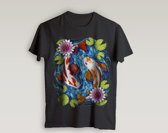May include: Black t-shirt featuring a vibrant illustration of two koi fish swimming in a pond with water lilies and lotus flowers. The fish are orange, white, and red, set against a blue background.