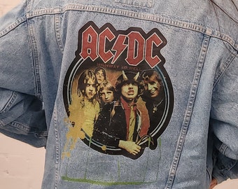 May include: A light blue denim jacket with an AC/DC patch on the back. The patch features a black and white image of the band members with the text "AC/DC" and "Highway to Hell" in red.
