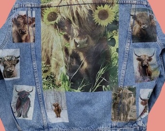 May include: A blue denim jacket with a patchwork design featuring multiple images of Highland cows. The images are printed on the back of the jacket and include a cow with sunflowers, a cow in a snowy forest, and a cow with a floral crown.