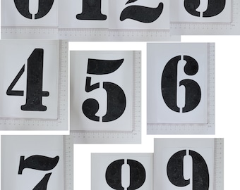 May include: Nine black stencils of numbers 0 through 9. The stencils are on white paper and are approximately 10 inches tall.