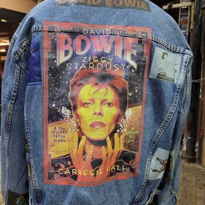 May include: A blue denim jacket with a large printed patch featuring David Bowie, the text "David Bowie", "Ziggy Stardust", "& The Spiders From Mars", "28 September 1972", and "Carnegie Hall".