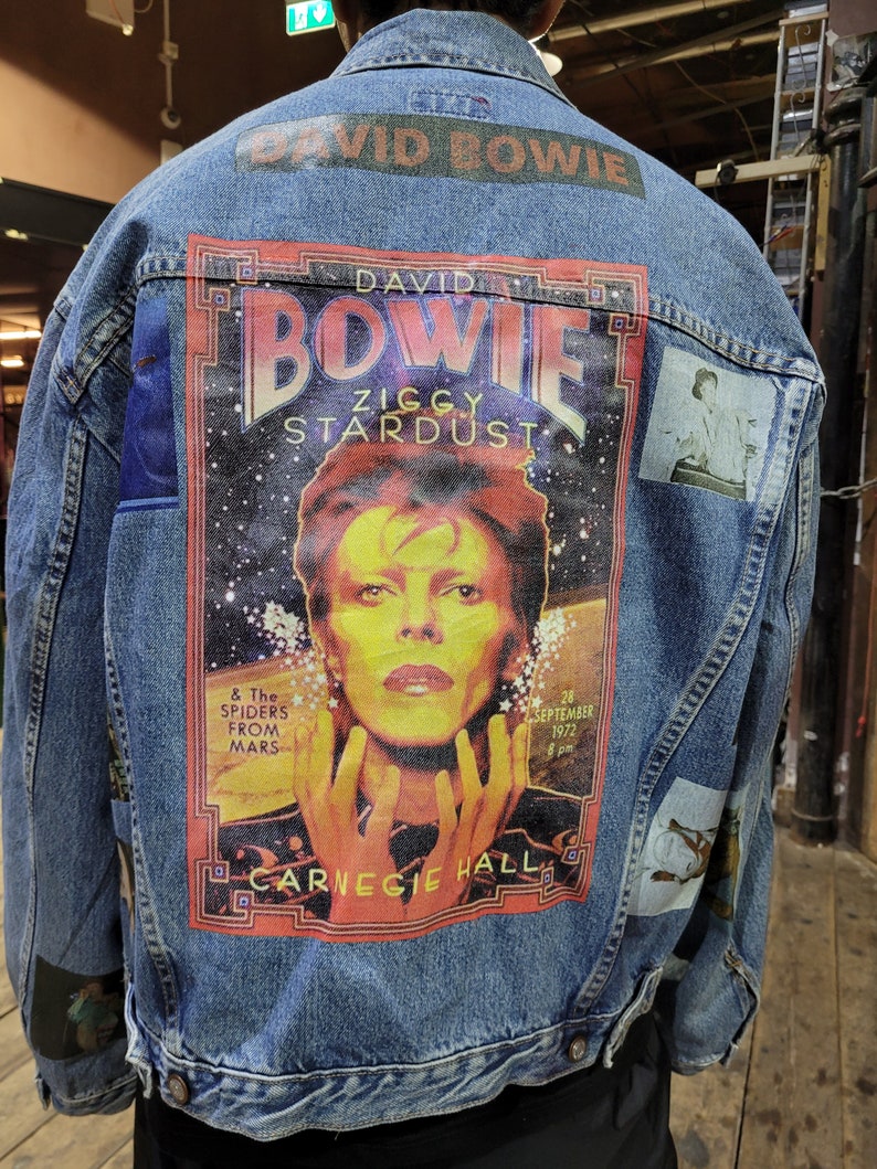 May include: A blue denim jacket with a large printed patch featuring David Bowie, the text "David Bowie", "Ziggy Stardust", "& The Spiders From Mars", "28 September 1972", and "Carnegie Hall".