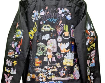 Op de afbeelding: Zwarte nylon jas met kleurrijke grafische illustraties. De achterkant toont de woorden "Hello Spring" omringd door bloemen en grillige afbeeldingen. Mouwen zijn versierd met diverse cartoon-achtige afbeeldingen. Een jas met kraag en ritssluiting.
