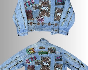 May include: Light blue denim jacket with graffiti art. The back of the jacket features colorful designs, including an eye, the word "POISON", and the word "LOVE". Barbed wire and roses are also painted on the jacket.