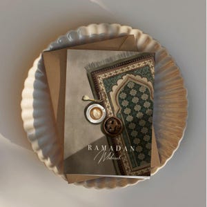 May include: A greeting card with a green and brown patterned prayer rug, a cup of coffee, and dates. The card says "Ramadan Mubarak".