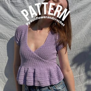 May include: A lilac-colored crochet top with a wrap-style front and short sleeves. The top features a peplum hem and is made of a textured yarn. The word "PATTERN" is displayed in white text across the top, with "By sunflowerandcrochet" below it.