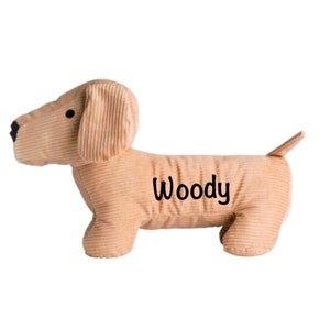 Könnte beinhalten: Ein brauner Cord-Dackel-Türstopper mit dem Namen "Woody", der auf die Seite gestickt ist.