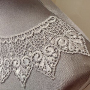 Può includere: Bordino in pizzo bianco con un bordo a festoni. Il pizzo è delicato e intricato, con un motivo floreale.